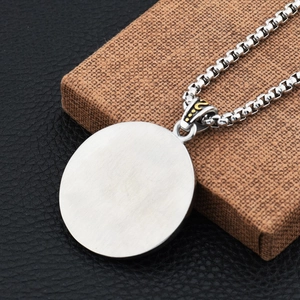 Macro shot of circular brushed stainless steel pendant with box chain on jewelry box