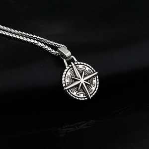 Vintage stainless steel compass pendant necklace with starburst design on black background