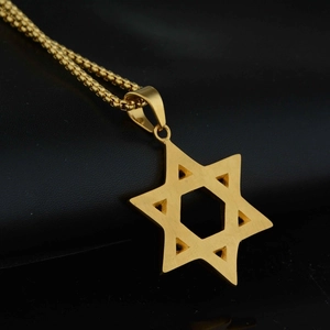 Gros plan d'un pendentif étoile hexagonale dorée avec chaîne box sur cuir noir mat