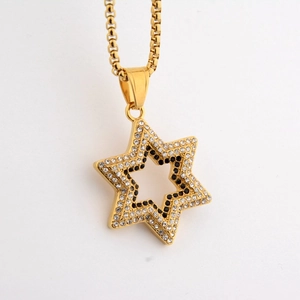 Macro detail of gold hexagram pendant with black and white cubic zirconia stones