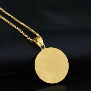 Macro detail of golden OM round pendant with brushed finish on a box chain necklace