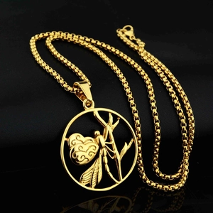 Detailaufnahme der goldenen Libellen-Anhänger-Halskette auf einem schwarzen Lederhintergrund