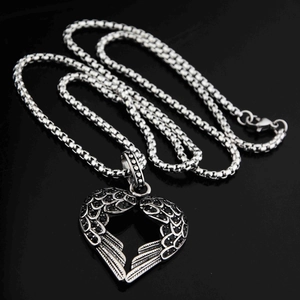 Vue macro du pendentif cœur plume avec pierres noires sur une surface brillante