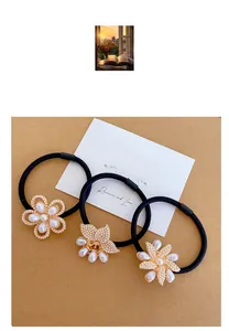 Detail of three black elastic hair ties with gold flower charms and faux pearls