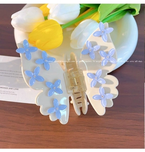 Dettaglio molletta a farfalla color crema con piccoli fiori viola 3D e strass scintillanti