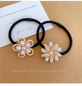 Detail view of pearl flower hair ties with gold metal base on vintage paper