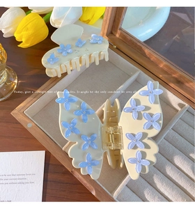 Dettaglio delle pinze per capelli crema con fiori 3D blu in una scatola di legno