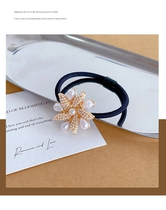 Detail of elegant pearl flower hair tie with golden base on decorative card