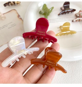 Detail showing mini acetate hair claws in various colors held in hand for scale