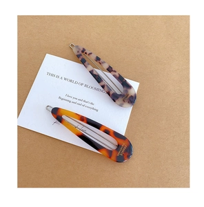 Detail view of two French vintage tortoiseshell hair clips with hollow teardrop design