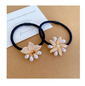 Detail of floral hair ties with pearl charms and gold accents on a set of black bands