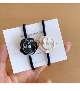 Dettaglio degli elastici per capelli con camelia bordata d'oro e perle bianche