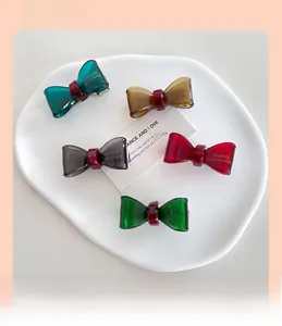 Close-up of five colorful bow-shaped resin hair clips on a white ceramic plate