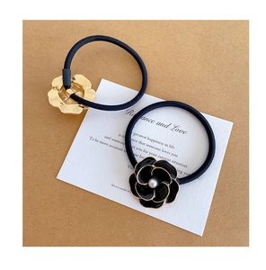 Dettaglio di elastici per capelli camelia con smalto nero e accenti di perle finte