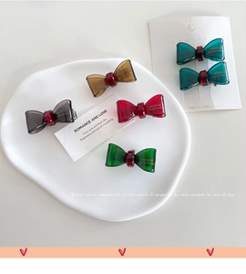 Detailed macro view of colorful mini resin bow hair clips with golden handmade engraving