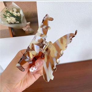 Détail de la pince à cheveux papillon avec texture marbrée ambre et ressort en métal