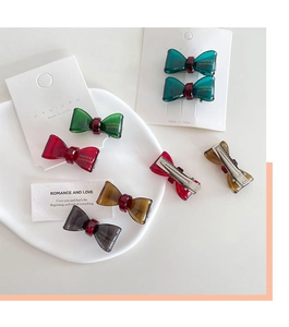 Detail of colorful resin bow hair clips with handmade text and metal alligator grip