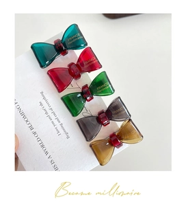 Macro detail of five translucent resin bow hair clips in assorted colors on a card