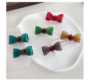 Detailed close-up of colorful resin bow hair clips in red green amber and gray