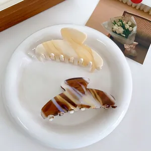 Lot de deux pinces à cheveux en acétate crème et marron café avec une élégante étiquette dorée