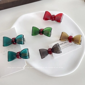 Cute resin bow hair clips set with gold lettering in a decorative white dish