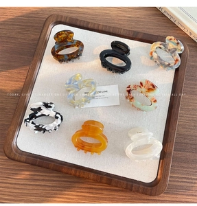 Close-up of eight handmade floral acetate hair claws in various patterns on a tray
