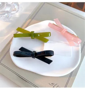 Detailed shot of glossy pink green and black bow hair clips on a white display tray