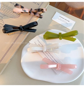 Detailed close-up of five colorful acetate bow hair clips in chic French style patterns