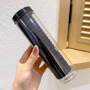 Macro detail of high-elastic black hair ties in a transparent cylinder storage case