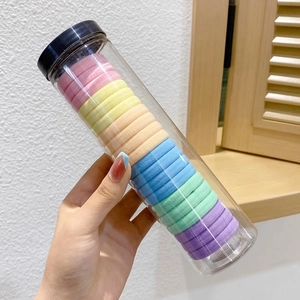 Macro detail of high-elastic seamless hair ties in a clear cylinder with macaron colors