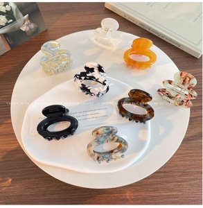Set of eight assorted floral and marble acetate hair claws displayed on a ceramic tray