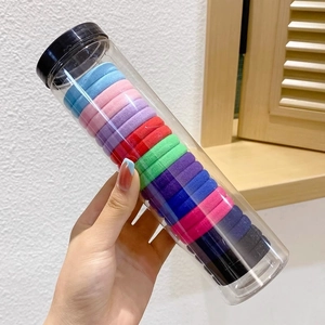 Detailed view of colorful high-elastic hair ties in a transparent cylinder storage bottle