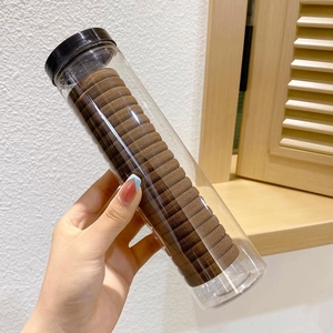 Macro shot of durable brown high-elastic hair ties in a clear storage cylinder bottle