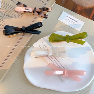Classic French acetate bow hair clips set in five elegant colors on aesthetic book display