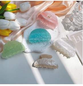 Detalle de cinco pinzas de pelo semicirculares en tonos pastel efecto mármol