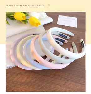 Detail of five macaron-colored sponge headbands with handmade tags on wooden display