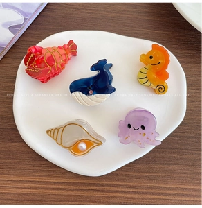 Detailed close-up of marine acetate hair clips featuring dolphin and starfish designs