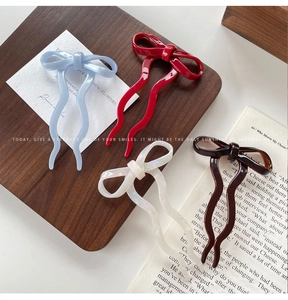 Close-up of four colorful bow hair pins in blue, red, pearl, and brown on a vintage background