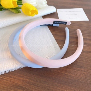 Minimalist handmade fabric headbands in pastel pink and blue on a wooden table