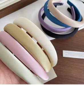 Dettaglio di cerchietti in raso colorato con marchio fatto a mano su legno scuro