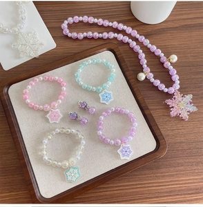 Détail d'une parure de bijoux enfant avec flocons de neige et perles en résine