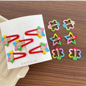 Close-up of colorful metal flower and star hair clips set on wooden background