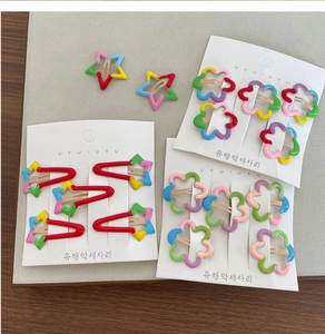 Close-up of colorful metal star and flower hair clips set on a display card