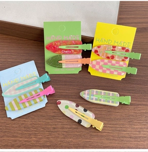 Détail de barrettes en acrylique colorées avec motifs cerise et carreaux sur bois