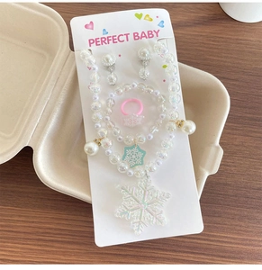 Vue détaillée du set de bijoux en perles irisées avec pendentifs flocon de neige sur carte