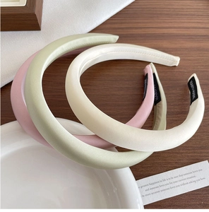 Dettaglio di tre cerchietti in raso imbottiti rosa verdi e beige con etichette fatte a mano