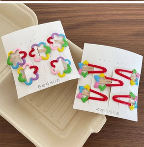 Close-up of rainbow flower and star hair clips for kids on a white display card