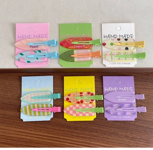 Détail du lot de 12 barrettes en résine colorée aux motifs de fruits et géométriques