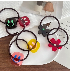 Nahaufnahme bunter Acryl-Haargummis mit Smileys und Blumenmotiven für Damen