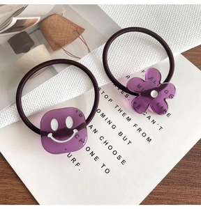 Detail von lila Harzblumen und Smiley-Würfeln an elastischen Haargummis im Set